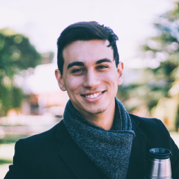 a shot haired man with a scarf is smiling.