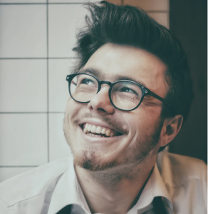 a man with glasses, short hair and short beard is smiling.