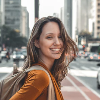 a blonde woman with a backpack smiling.